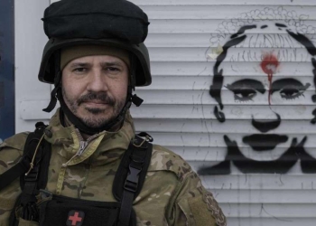 Militare ucraino accanto a una caricatura di Putin (LaPresse)