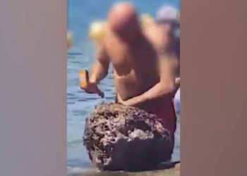 Prende scoglio a martellate per portar via datteri di mare