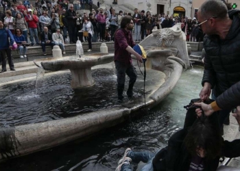 Attivisti di Ultima Generazione mentre sporcano con vernice nera la fontana della Barcaccia in Piazza di Spagna a Roma (LaPresse)