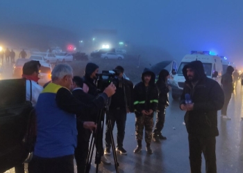 Soccorritori e giornalisti sul limitare dell'area in cui è disperso Raisi (Ansa)