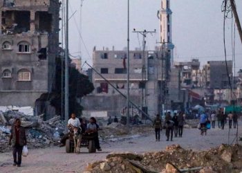 Sfollati palestinesi camminano per le rovine di Khan Younis (Ansa)