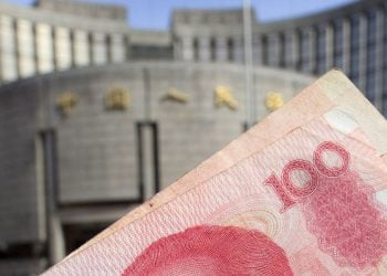 Banconota da 100 yuan renminbi. Sullo sfondo la PBOC (Ansa)