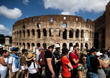 Turisti davanti al Colosseo di Roma (Ansa)