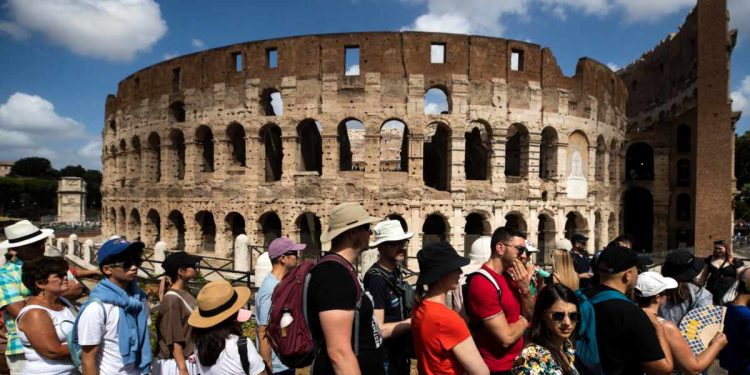 Turisti davanti al Colosseo di Roma (Ansa)