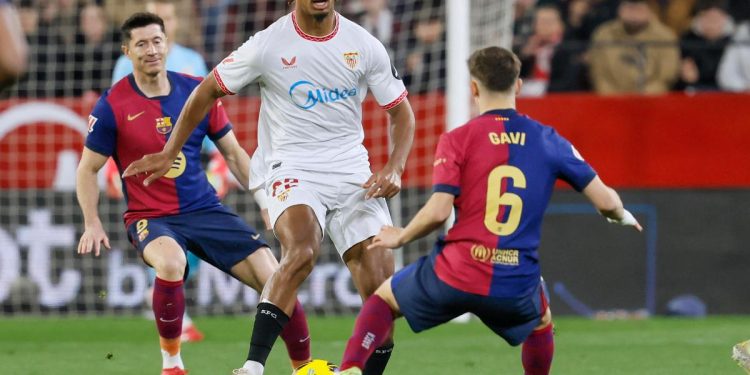 Loic Badé del Siviglia in mezzo a Gavi e Lewandowski (Foto Ansa)