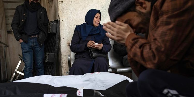 Famiglia palestinese piange i propri congiunti morti a seguito di un bombardamento israeliano sul campo profughi di Rafah, febbraio 2024 (Ansa)