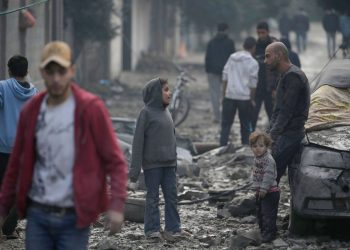 Un padre con in suoi figli nella Stirscia di Gaza dopo un bombardamento israeliano, 25 dicembre 2023 (Ansa)