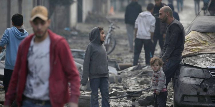 Un padre con in suoi figli nella Stirscia di Gaza dopo un bombardamento israeliano, 25 dicembre 2023 (Ansa)