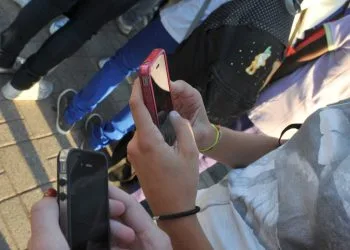 Studentesse all'ingresso della scuola con il telefonino (Ansa)