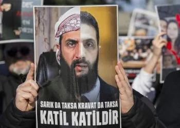 Cartello di protesta che ritrae il presidente siriano al Sharaa, (ex) jihadista dello Stato islamico (Ansa)